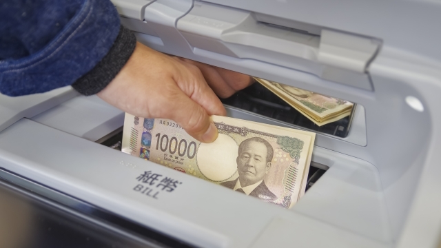 葬儀で振り込みされた補助金をATMから引き出しているシーン